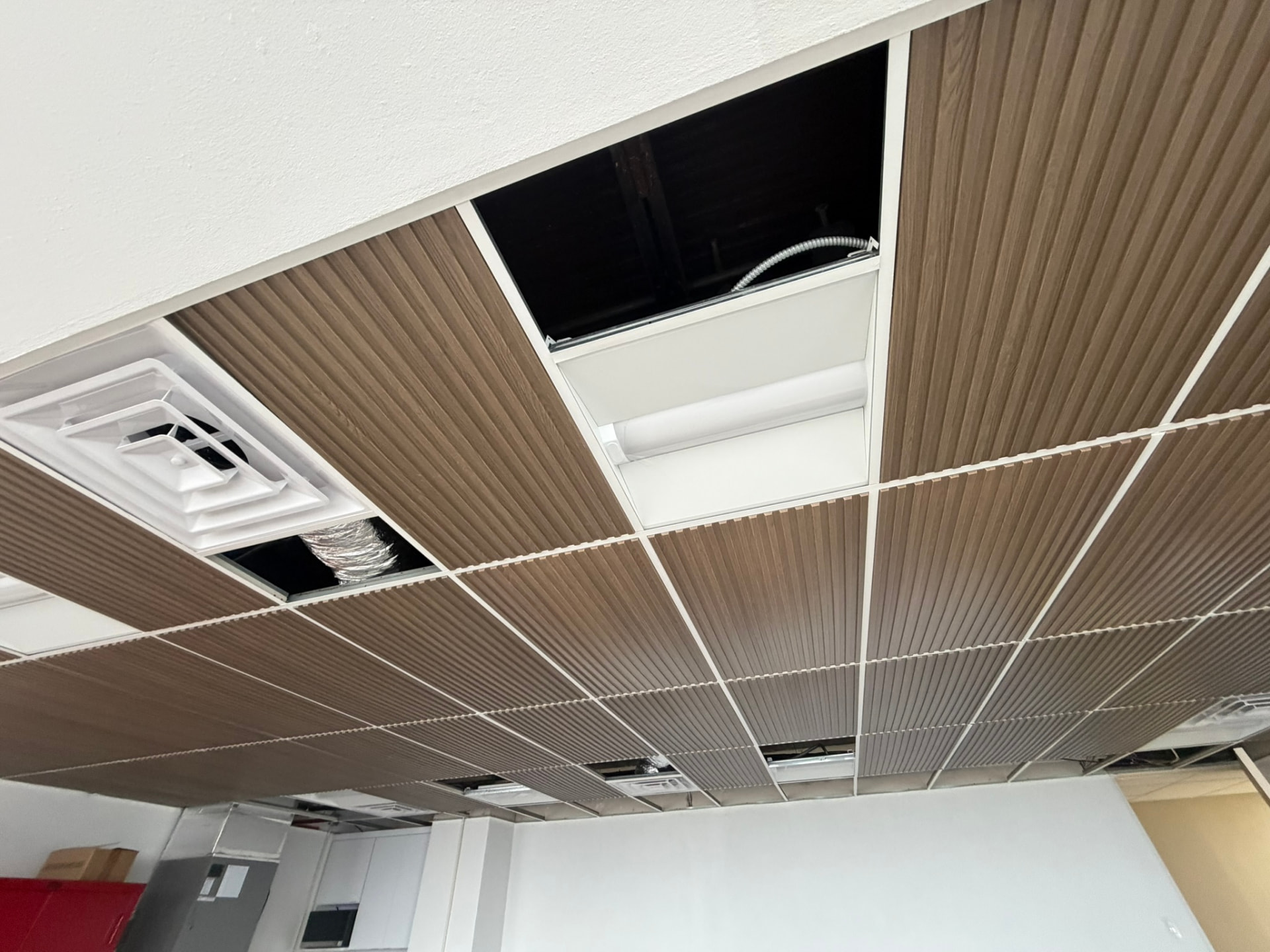 Instalación de plafón suspendido con paneles tipo madera en local comercial