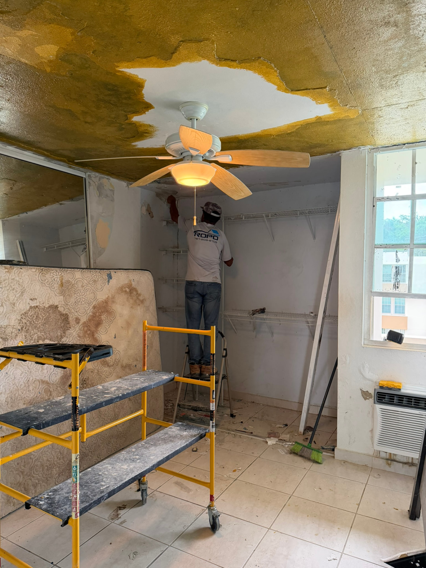 Técnico de ROPO removiendo techo dañado por filtración de agua en un cuarto