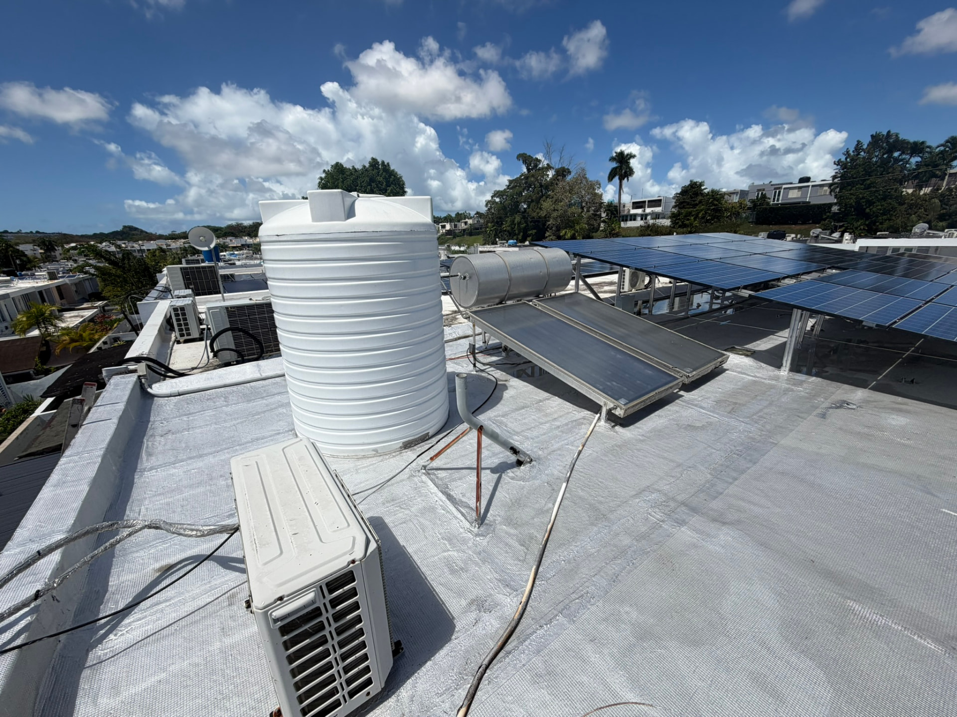 Techo sellado con acabado blanco alrededor de cisterna, calentador solar y placas solares