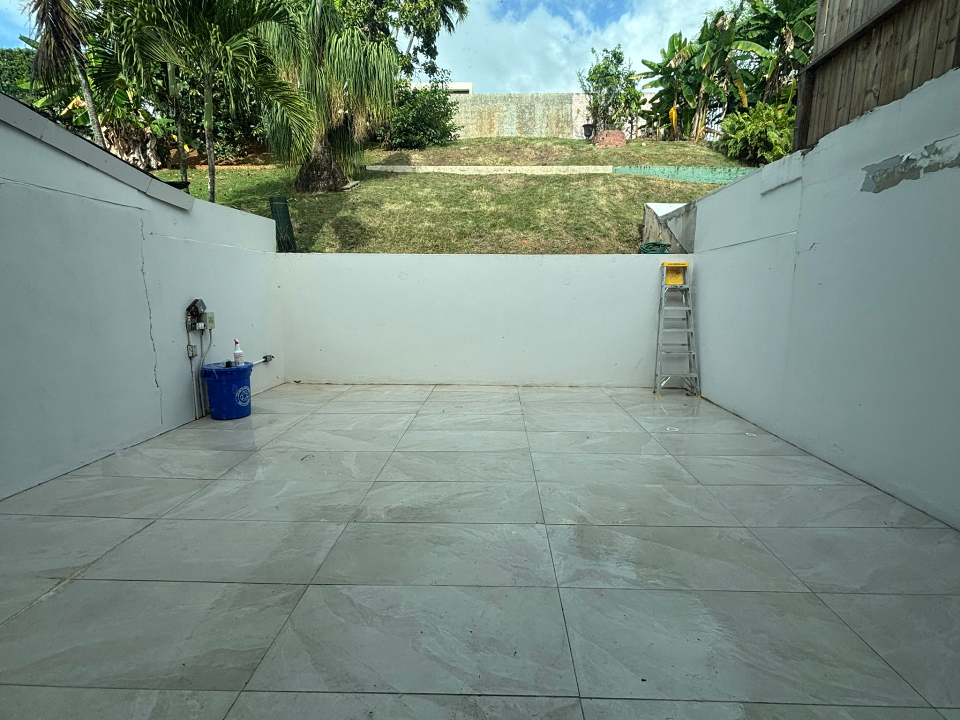 Patio terminado con losa de porcelana tipo mármol y paredes blancas