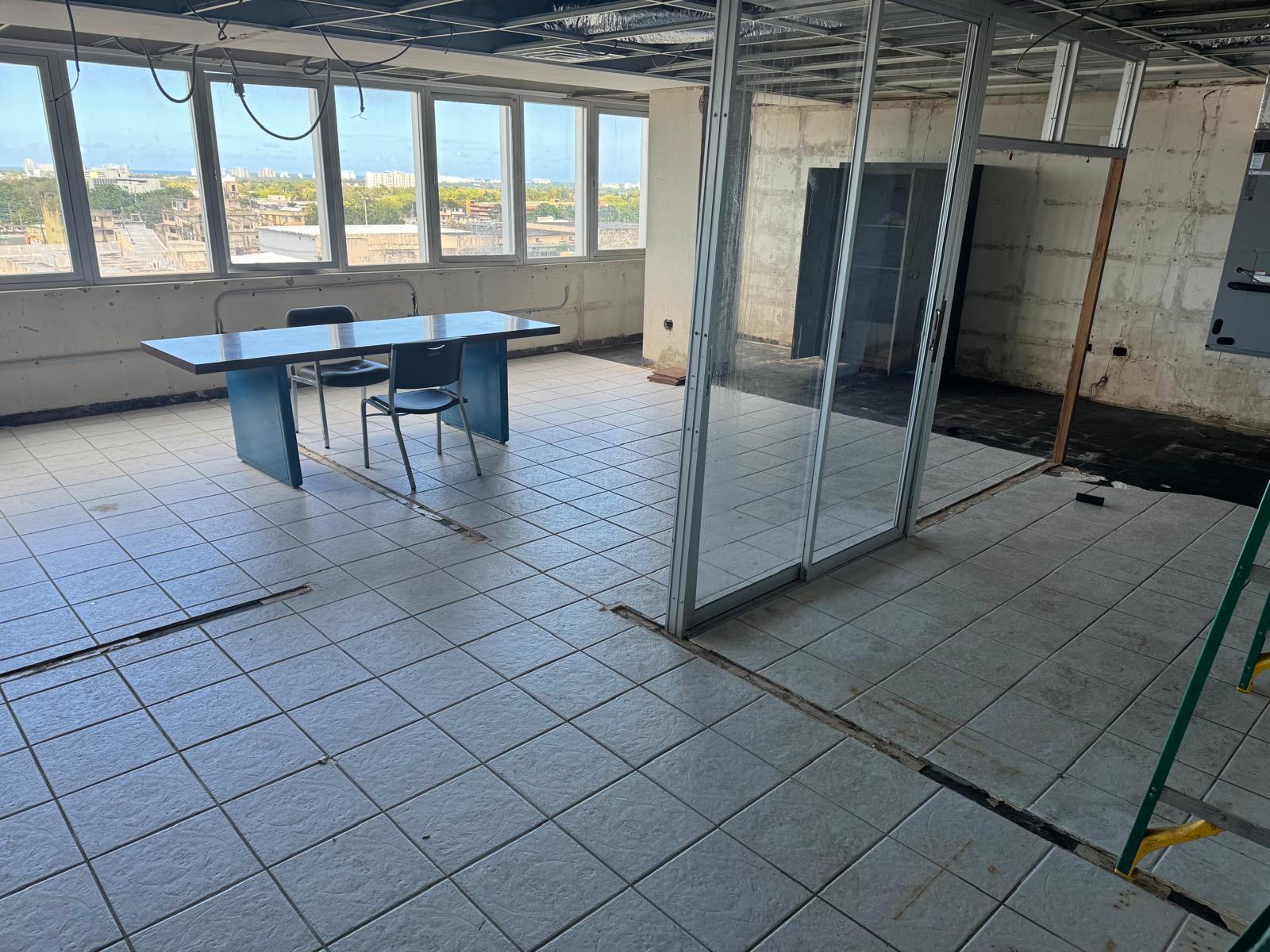 Oficina en obra con ventanales y vista a la ciudad antes de la remodelación