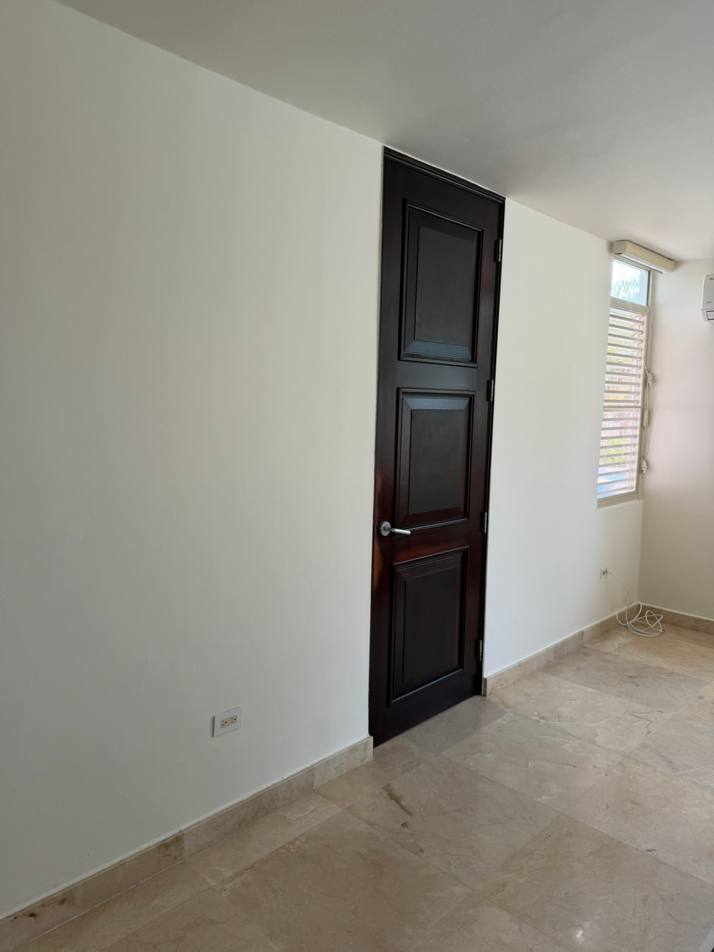 Cuarto terminado con puerta de madera oscura y piso de mármol pulido