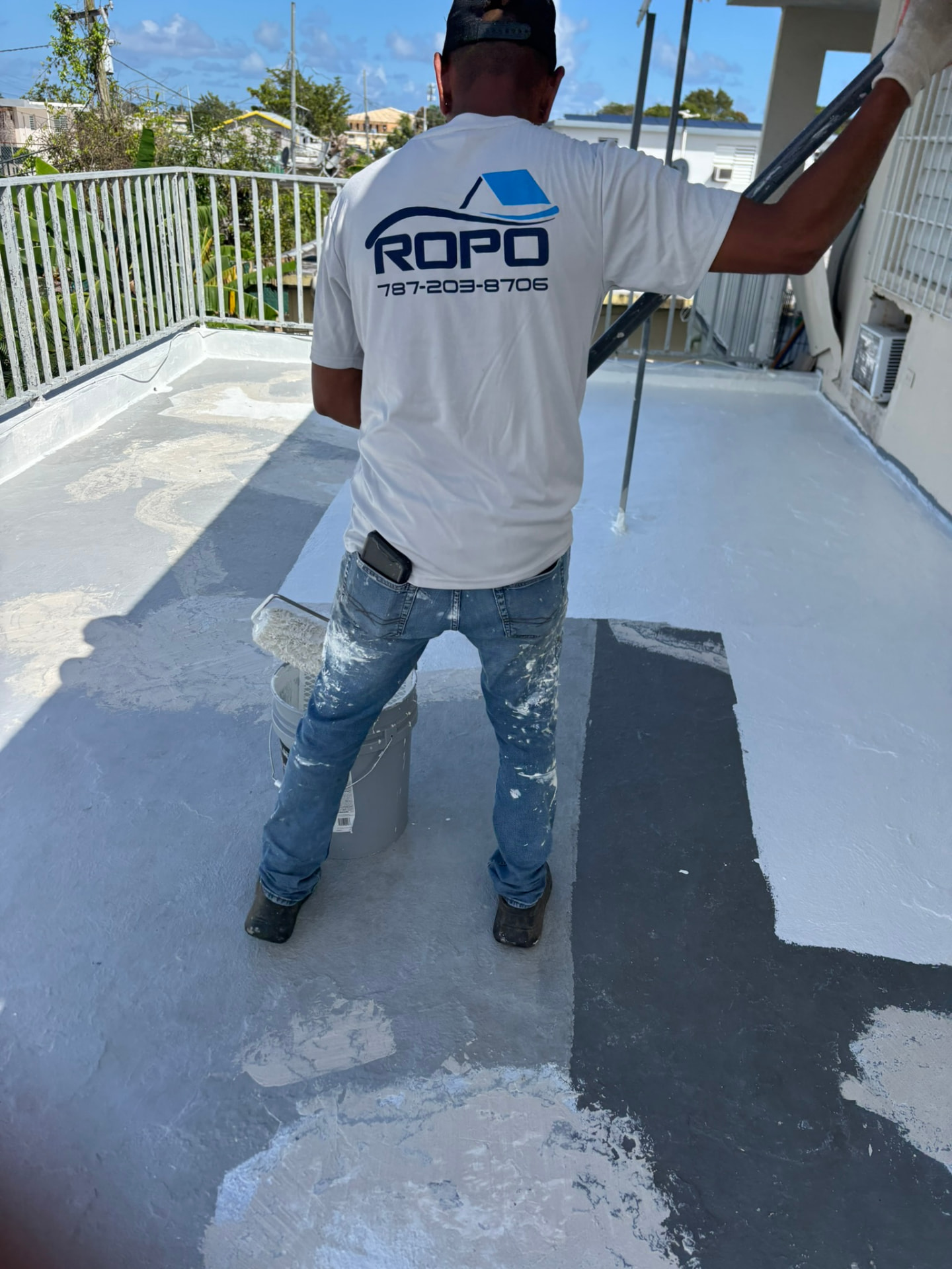 Técnico de ROPO aplicando sellador blanco con rodillo en una terraza