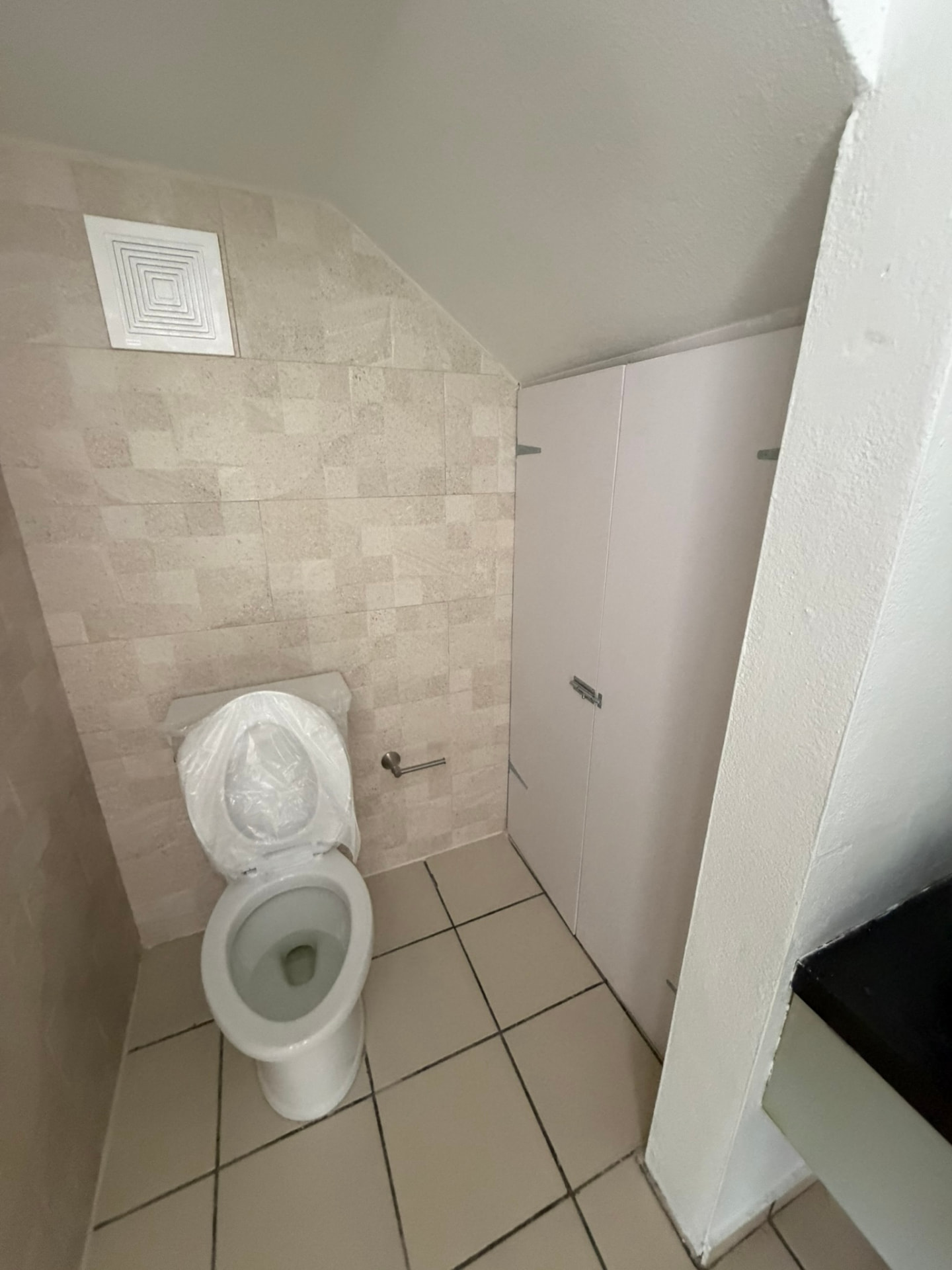 Baño pequeño terminado con losa travertino e inodoro nuevo