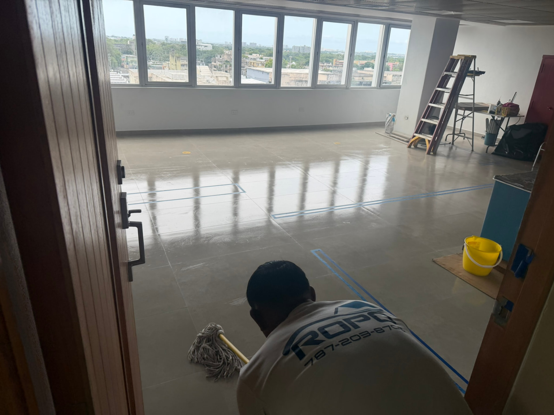Técnico de ROPO limpiando el piso de una oficina recién terminada