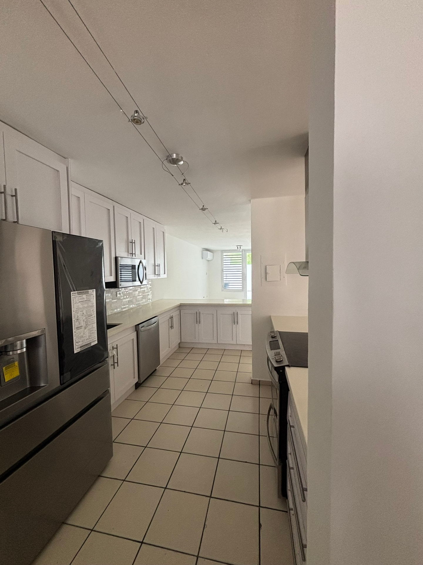 Cocina remodelada con gabinetes blancos, tope de cuarzo y enseres de acero inoxidable