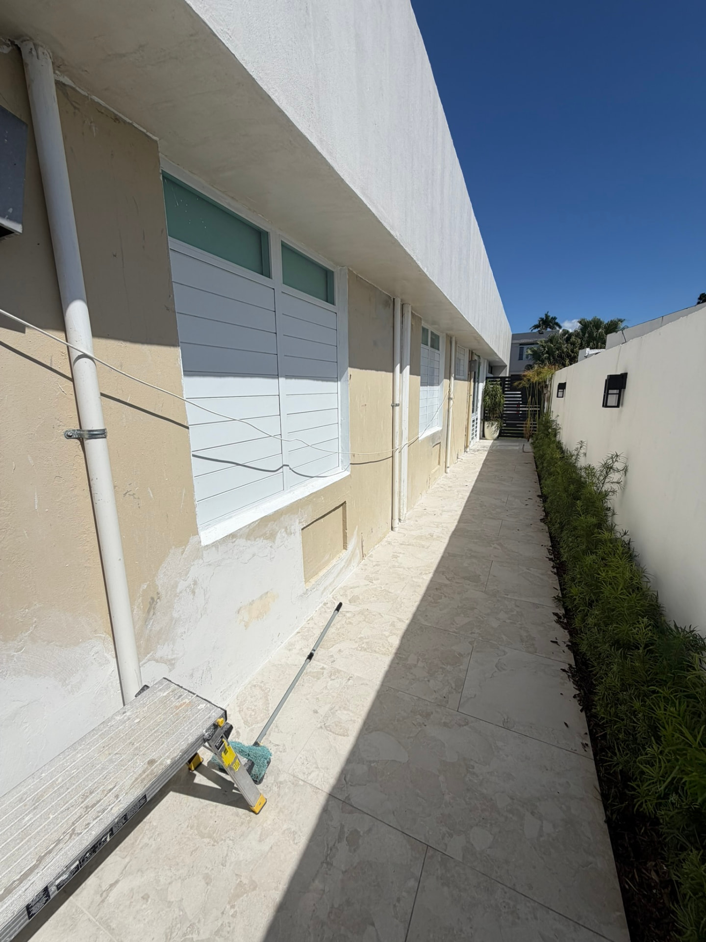 Exterior de residencia con preparación de paredes y ventanas para pintura