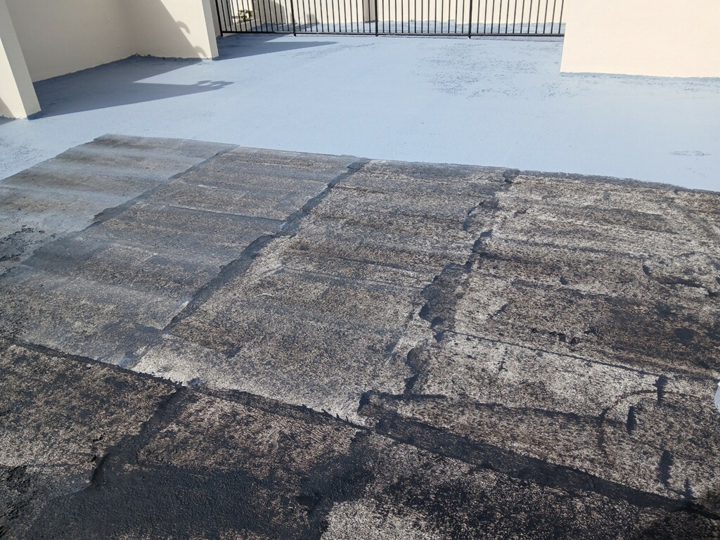Comparación de techo con manta asfáltica vieja y área nueva sellada en blanco