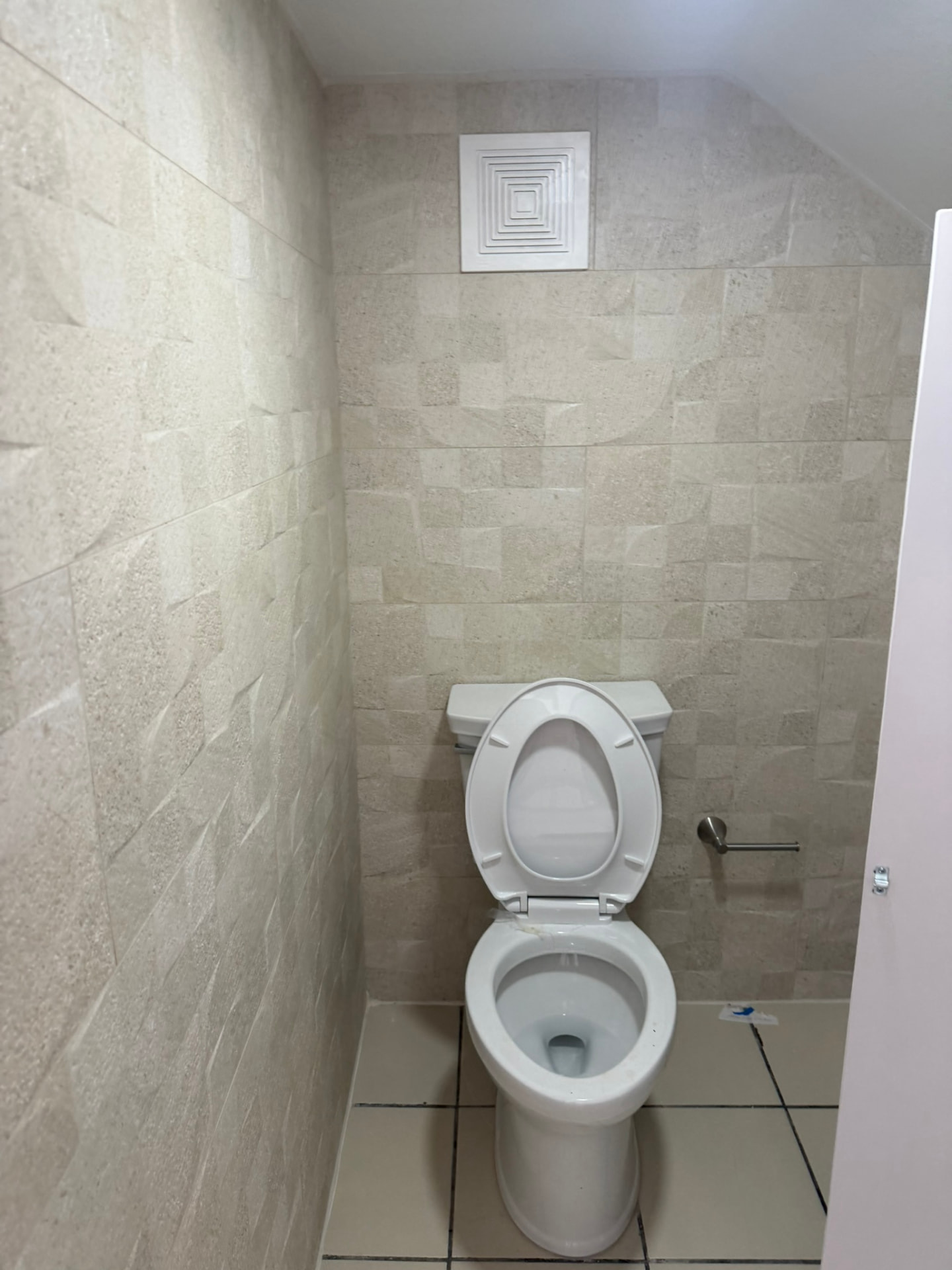 Baño con losa decorativa en pared e inodoro nuevo instalado