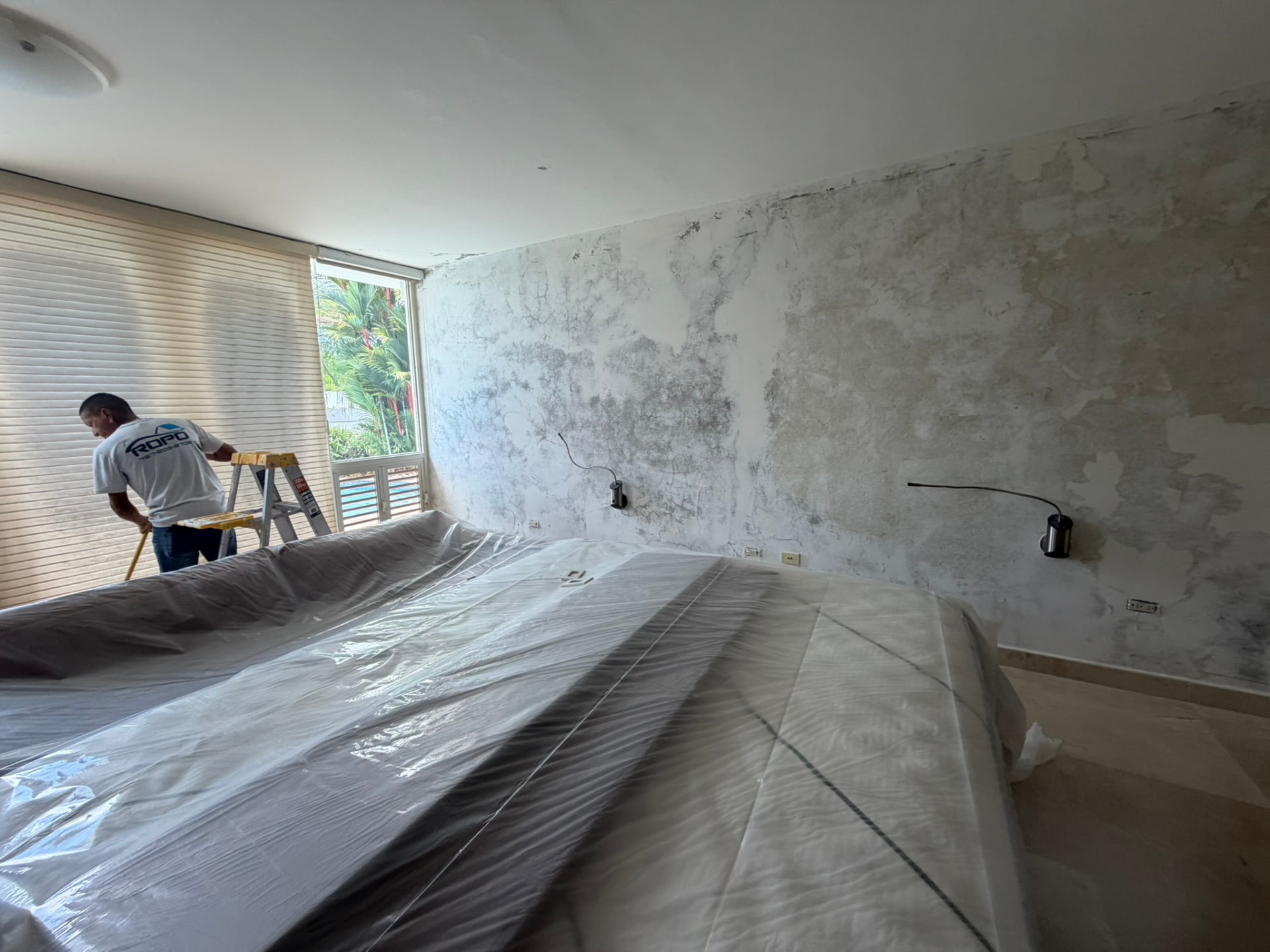 Preparación de pared con humedad y hongo en cuarto antes de sellar y pintar